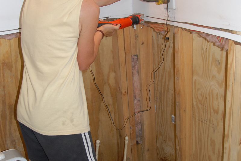 Homeowner cutting water-damaged sheetrock during cleanup